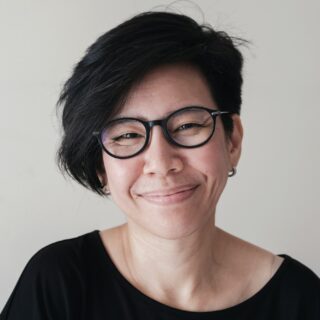 happy and healthy natural looking middle aged Asian woman wearing glasses and smiling at camera