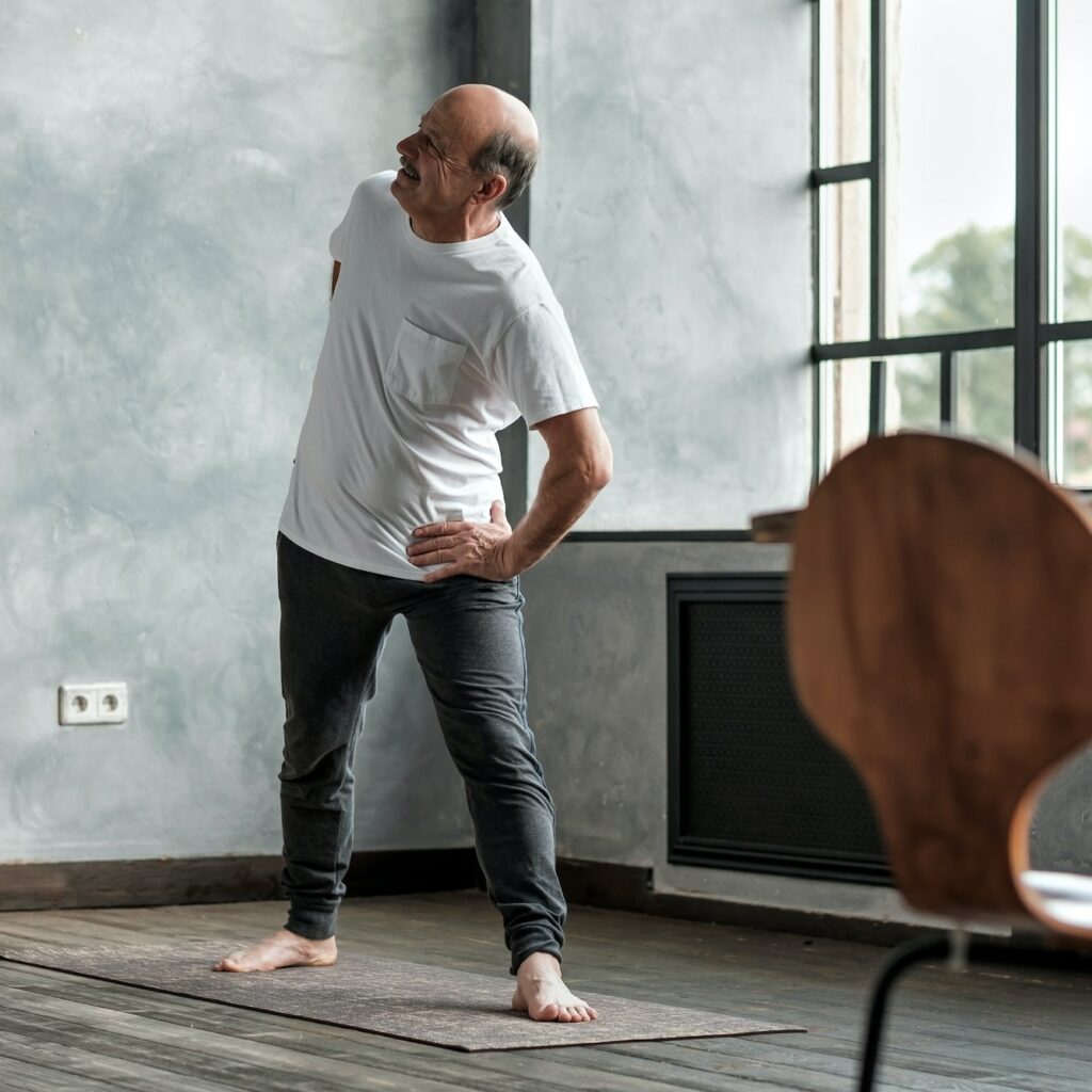 Elderly man practicing yoga or fitness during trikonasana.